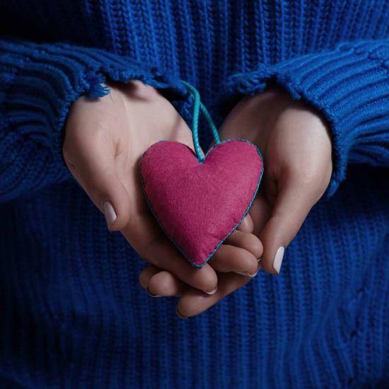 Woman holding fabric heart in hands