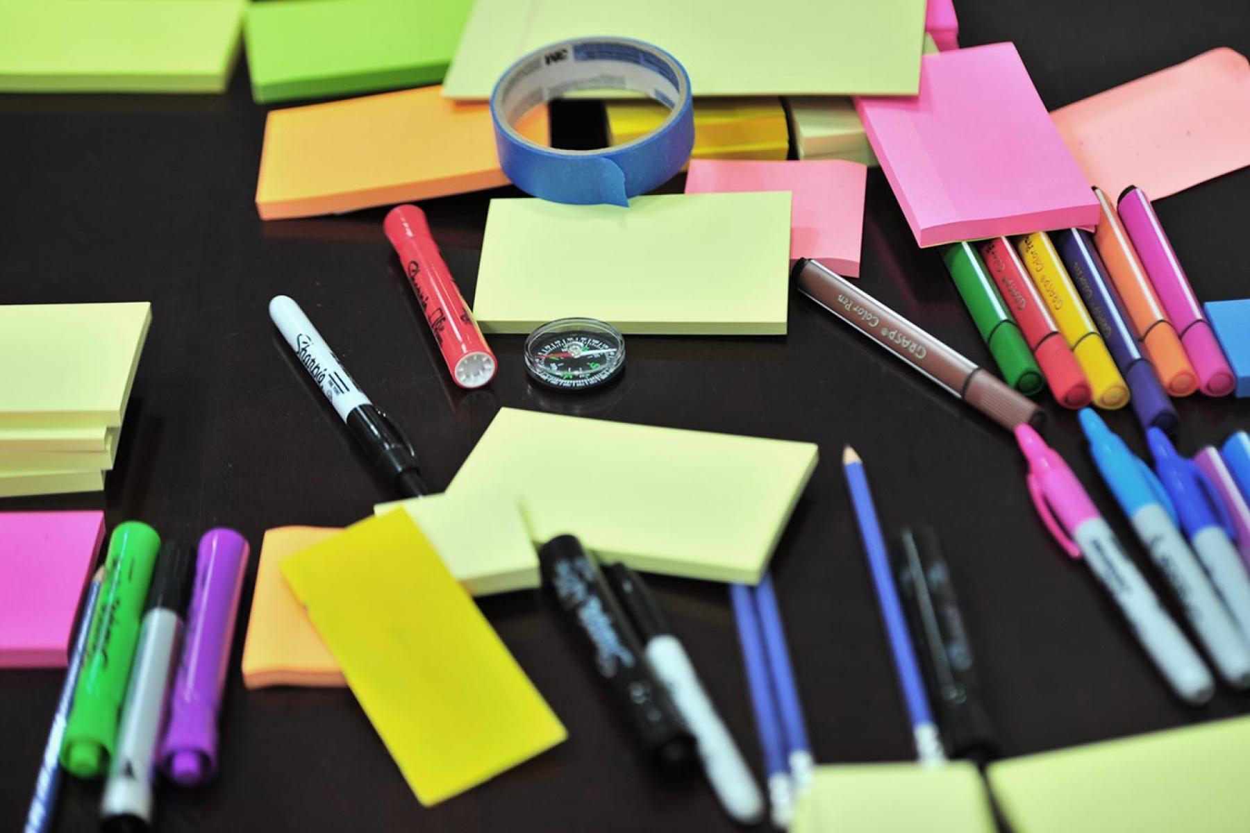 Brightly coloured post it notes and pens on a tabletop