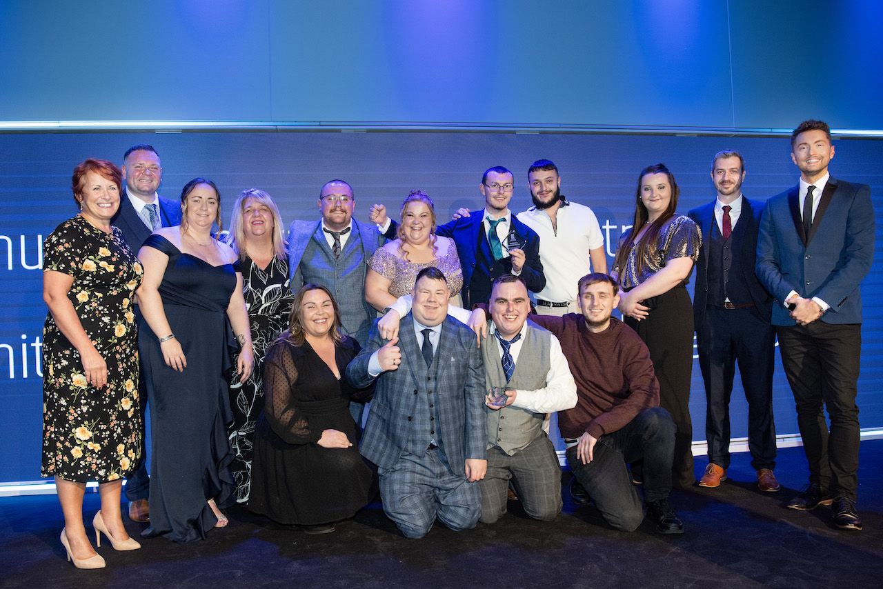 The Community Integrated Care services Chestnut Lane and Old Edinburgh Road teams in front of a blue banner 