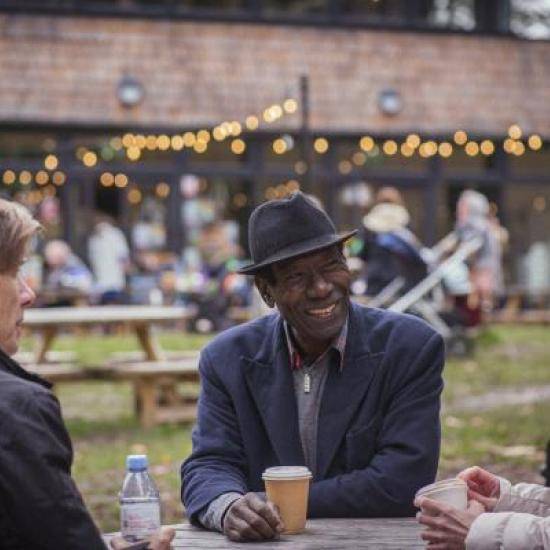 Three people sitting at a table at an outdoor event by Peter Kindersley