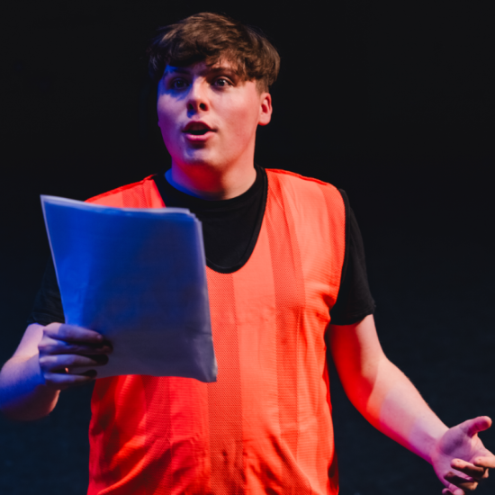 a man in a luminous orange vest reading from a script 