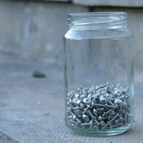 a jar of nuts and bolts on an exterior paved step