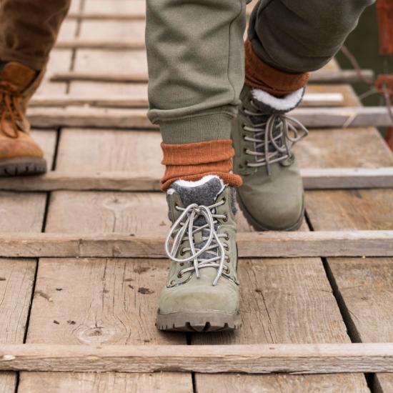 close up of two people's feet wearing hiking boots walking across a bridge
