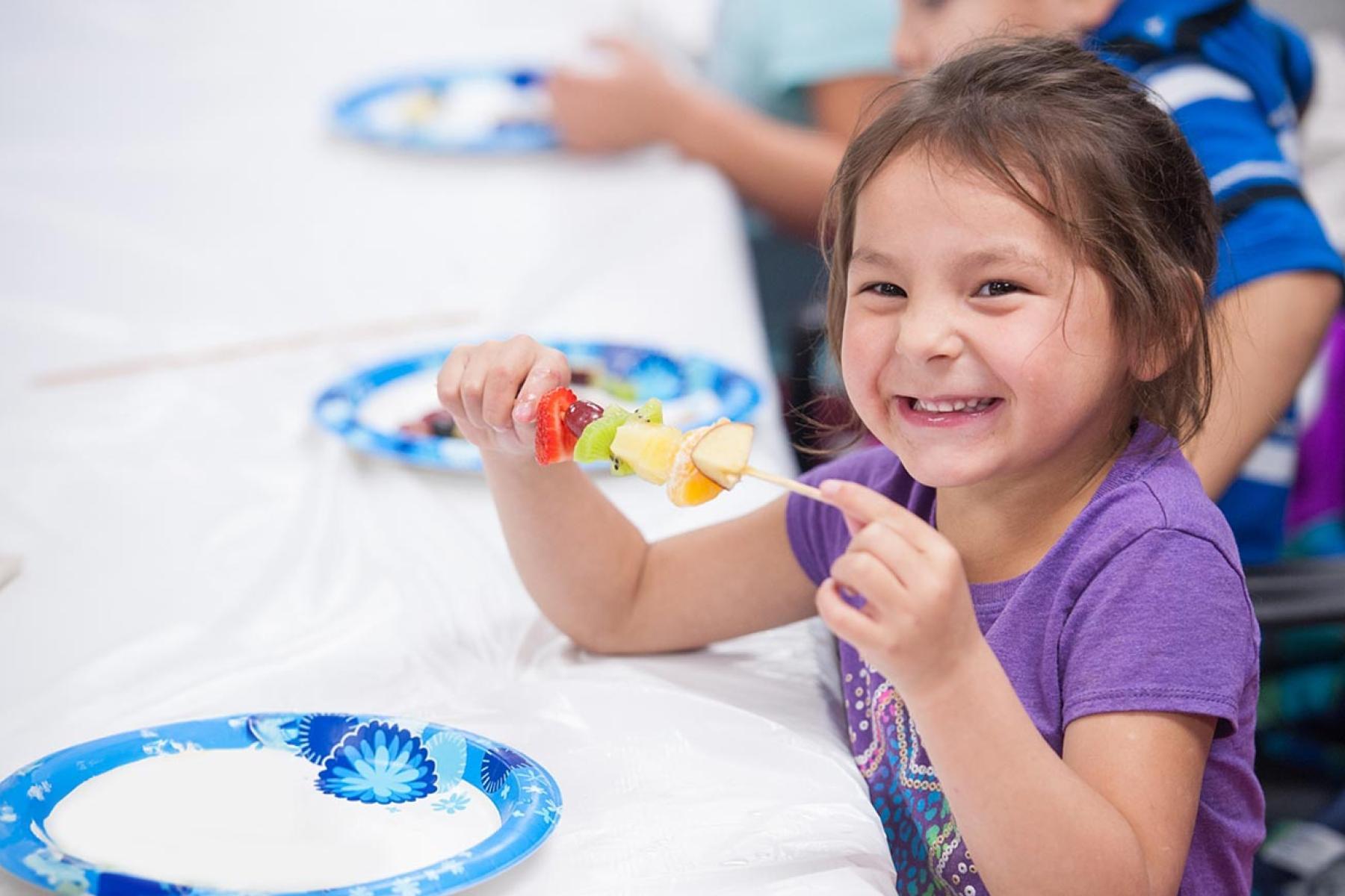 Young girl with fruit kebab smiling