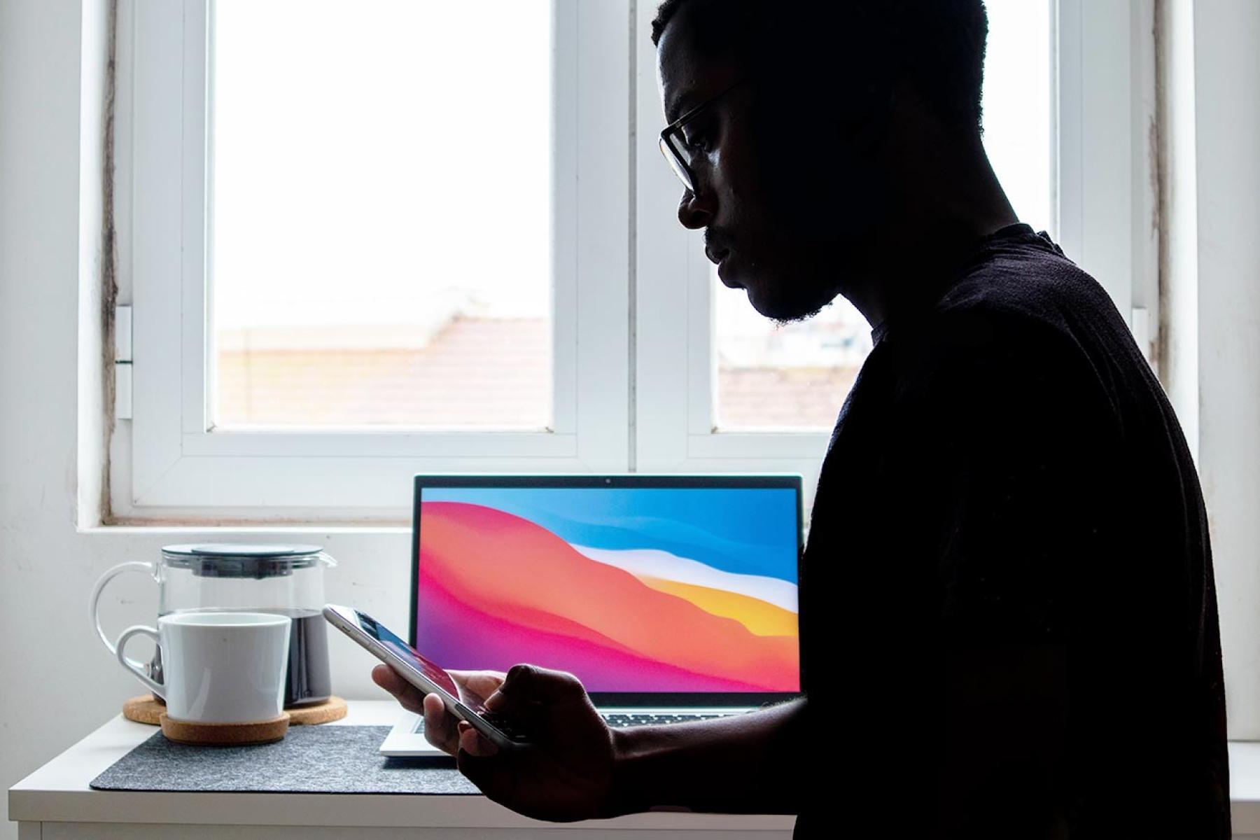 Man silhouetted at desk with coffee