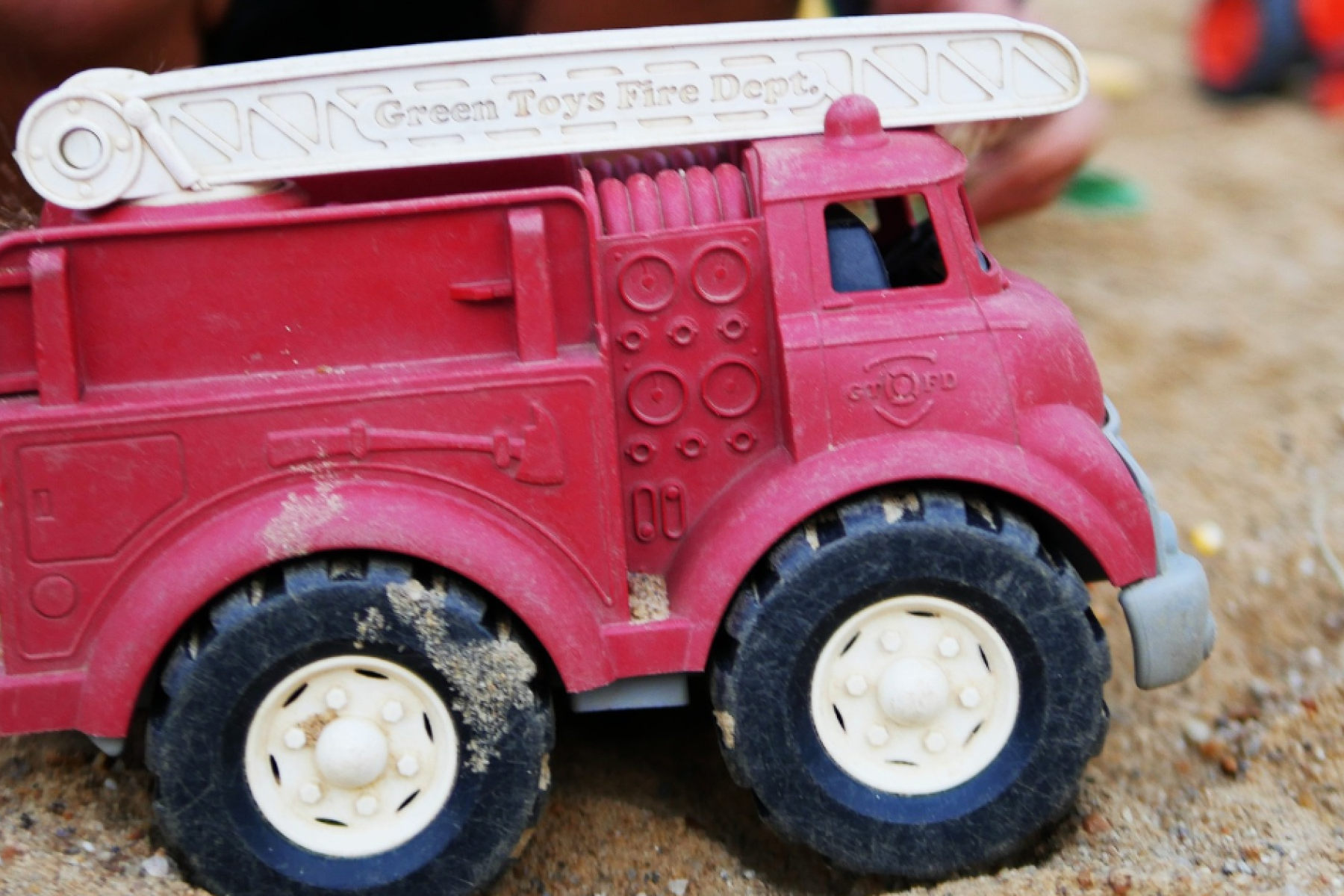 a toy fire truck in a sandpit