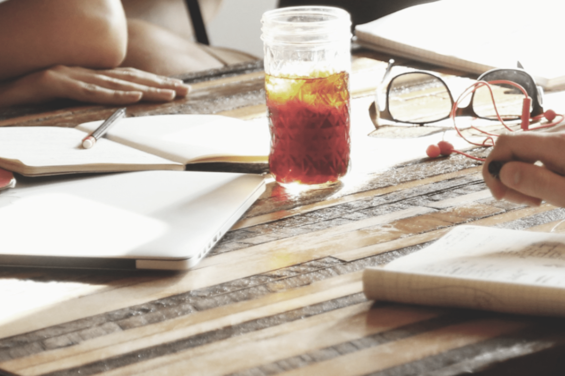 A table with notebooks and drinks as people are in discussion