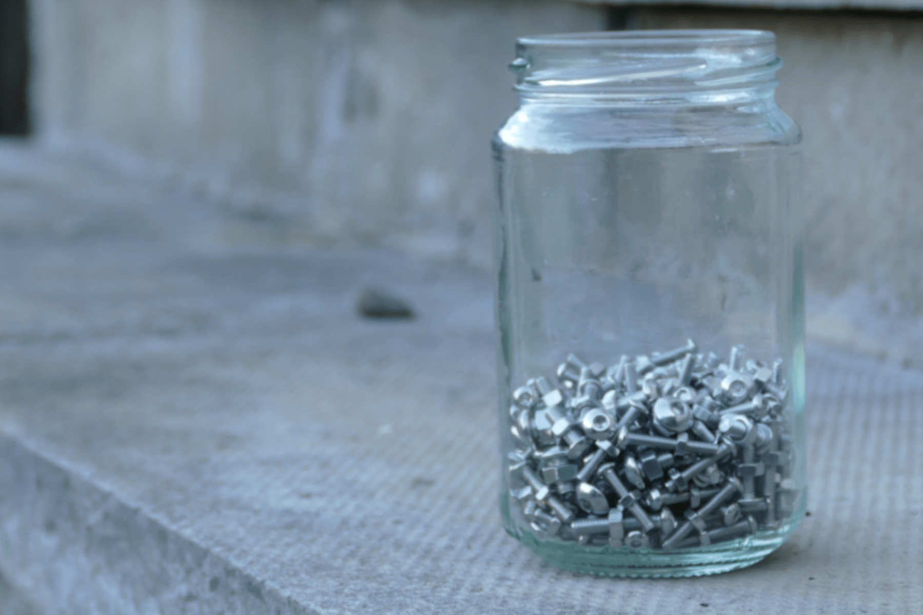 a jar of nuts and bolts on an exterior paved step