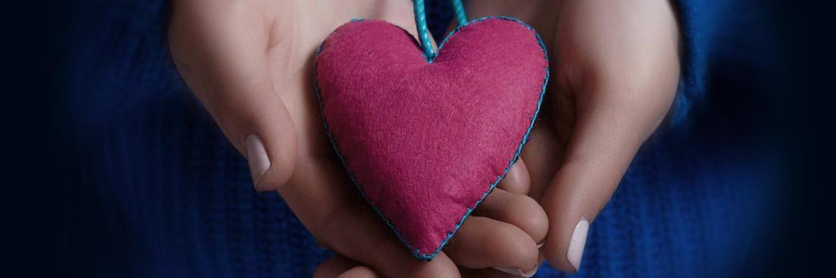 Woman holding fabric heart in hands