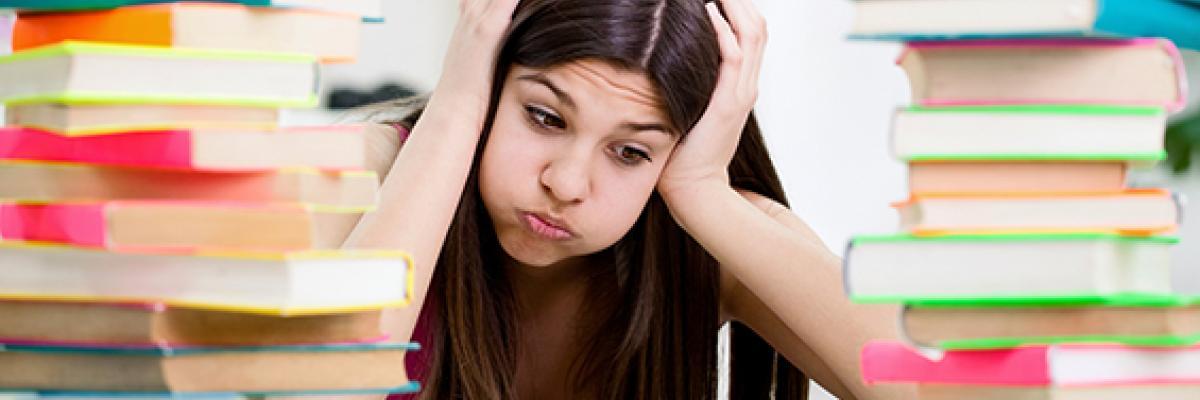 Student surrounded by books, looking confused