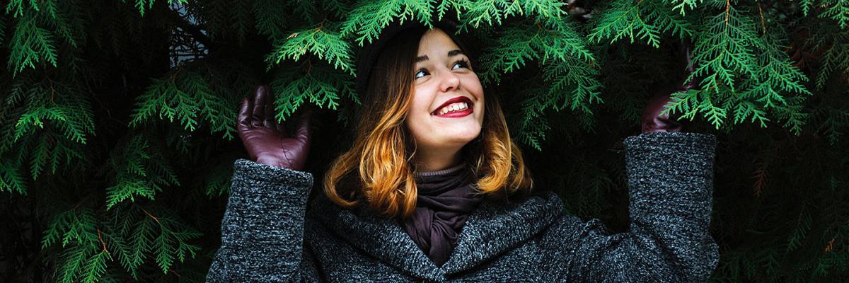 Smiling woman sheltering under trees