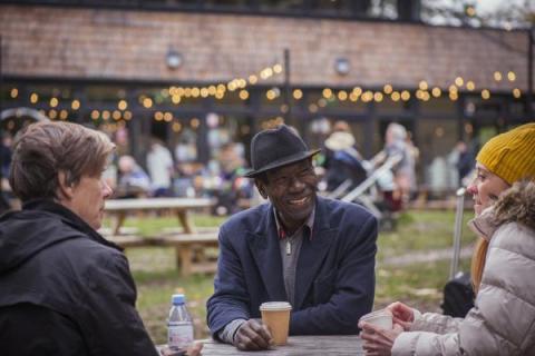 Three people sitting at a table at an outdoor event by Peter Kindersley