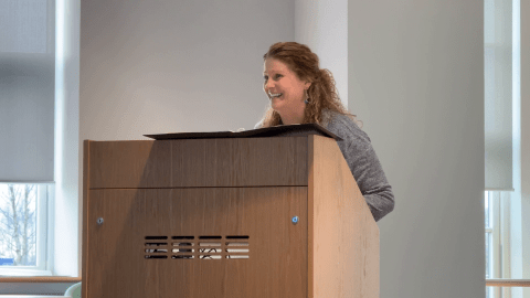 A lady smiles from behind a lectern