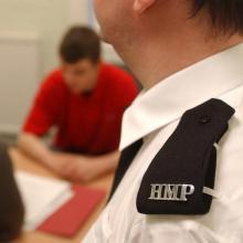 HMP prison guard watching prisoner interview