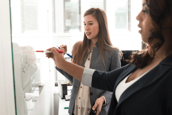 Image of two workers writing on a whiteboard